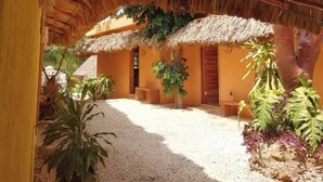 A thatched-roof structure with a gravel courtyard and potted plants. - Suites Casa de Piedra y Colores-Sak (Tinum)