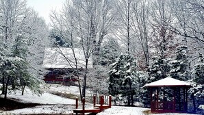Scena invernale con un gazebo, uno stagno e alberi coperti di neve.