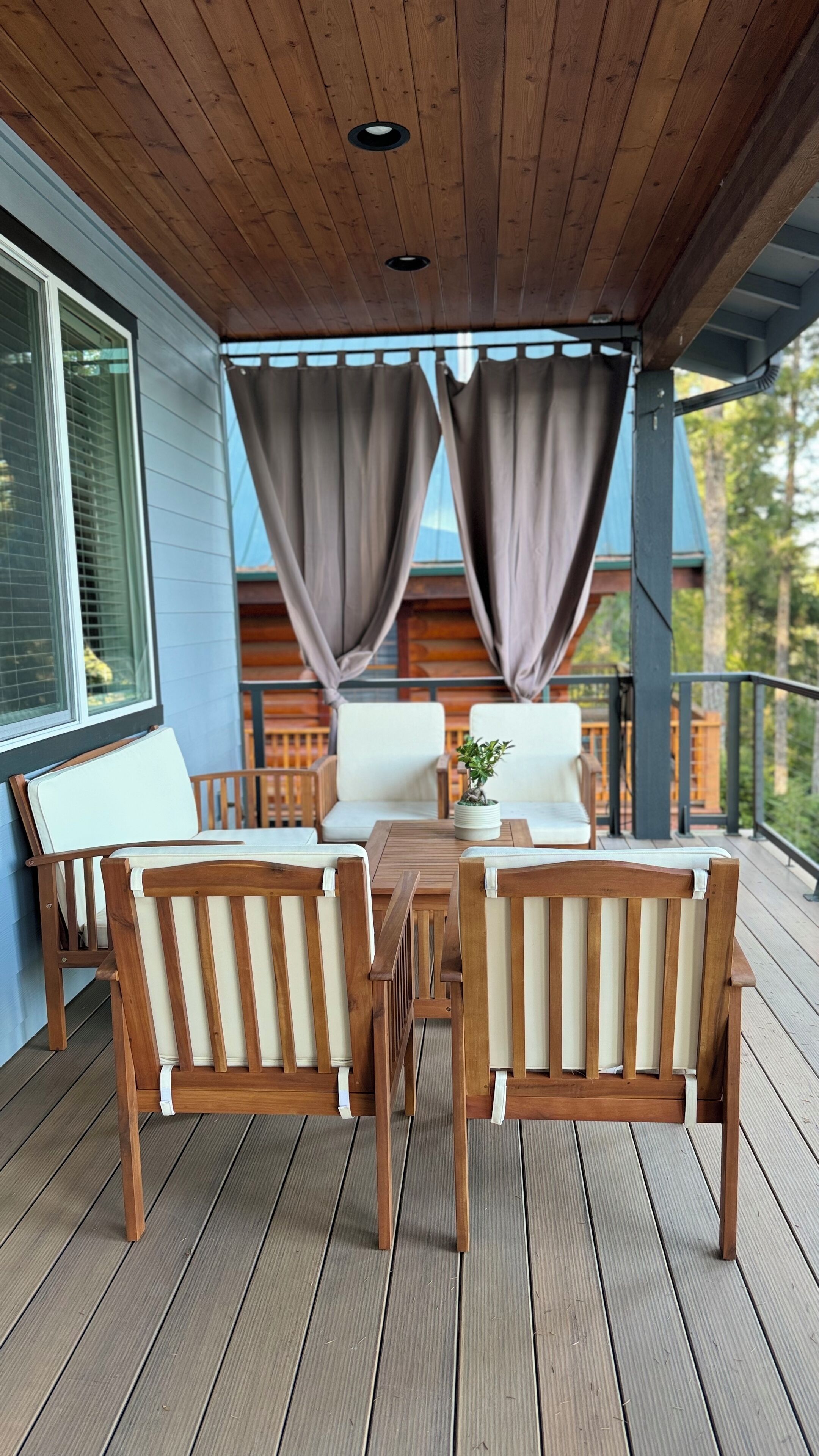 A covered outdoor seating area with wooden furniture and a view of a building in the background.