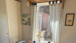 Un comedor con una mesa de madera, sillas, un florero y una ventana con cortinas.