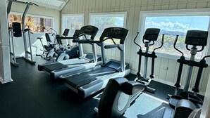 A gym with treadmills, elliptical machines, and a fan. - SeaDazzle-beachfront, pool, Jeep (St. Thomas)
