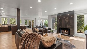 A modern living room with a fireplace, leather sofa, and dining area. - Ski Chalet • 4 bedroom • Beautifully Remodeled • Walk to Lifts (Park City)