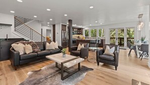 A modern living room with a sofa, armchairs, a coffee table, and a dining area with chairs and a table. - Ski Chalet • 4 bedroom • Beautifully Remodeled • Walk to Lifts (Park City)