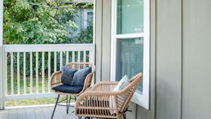 Eine Veranda mit zwei Korbstühlen, einem kleinen Teppich und einer grünen Hagebutten-Kugelform.
