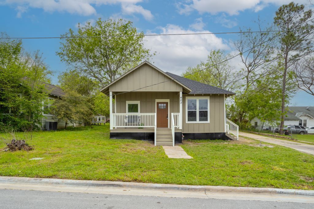 A single-story house with a front porch, a small front yard, and a clear sky.