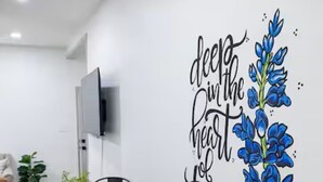 Ein Essbereich mit einem runden Tisch, schwarzen Stühlen und einem an der Wand befestigten Fernseher.