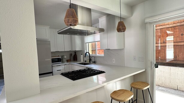 A modern kitchen with a central island, white cabinetry, and a large window.