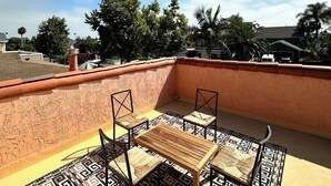 A rooftop terrace with a patterned floor, two chairs, and a table.