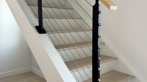 A modern staircase with wooden handrails and metal balusters.