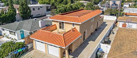 A residential building with a red-tiled roof, a garage, and a balcony.