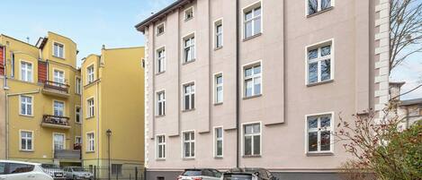 A multi-story residential building with a parking area in front.