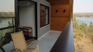 A balcony with a view of a lake, a wicker chair, and a small table. - Hotel Maravilha do Lago (Pedregulho)