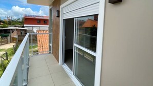 Un balcon doté d’une porte-fenêtre coulissante, un petit espace extérieur avec un sol carrelé et une vue sur les bâtiments voisins.