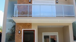 Un bâtiment à deux étages doté d’un balcon, d’une porte de garage et d’une petite fenêtre.