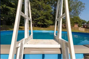 A swimming pool with a white deck and a ladder leading into the water. - Pool Near Fort Moore Our White House (Columbus)