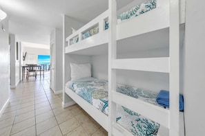 Una habitación con literas, una zona de comedor con sillas y una mesa, y vista al mar.