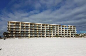 A large, multi-story hotel with a uniform exterior, located on a sandy beach.