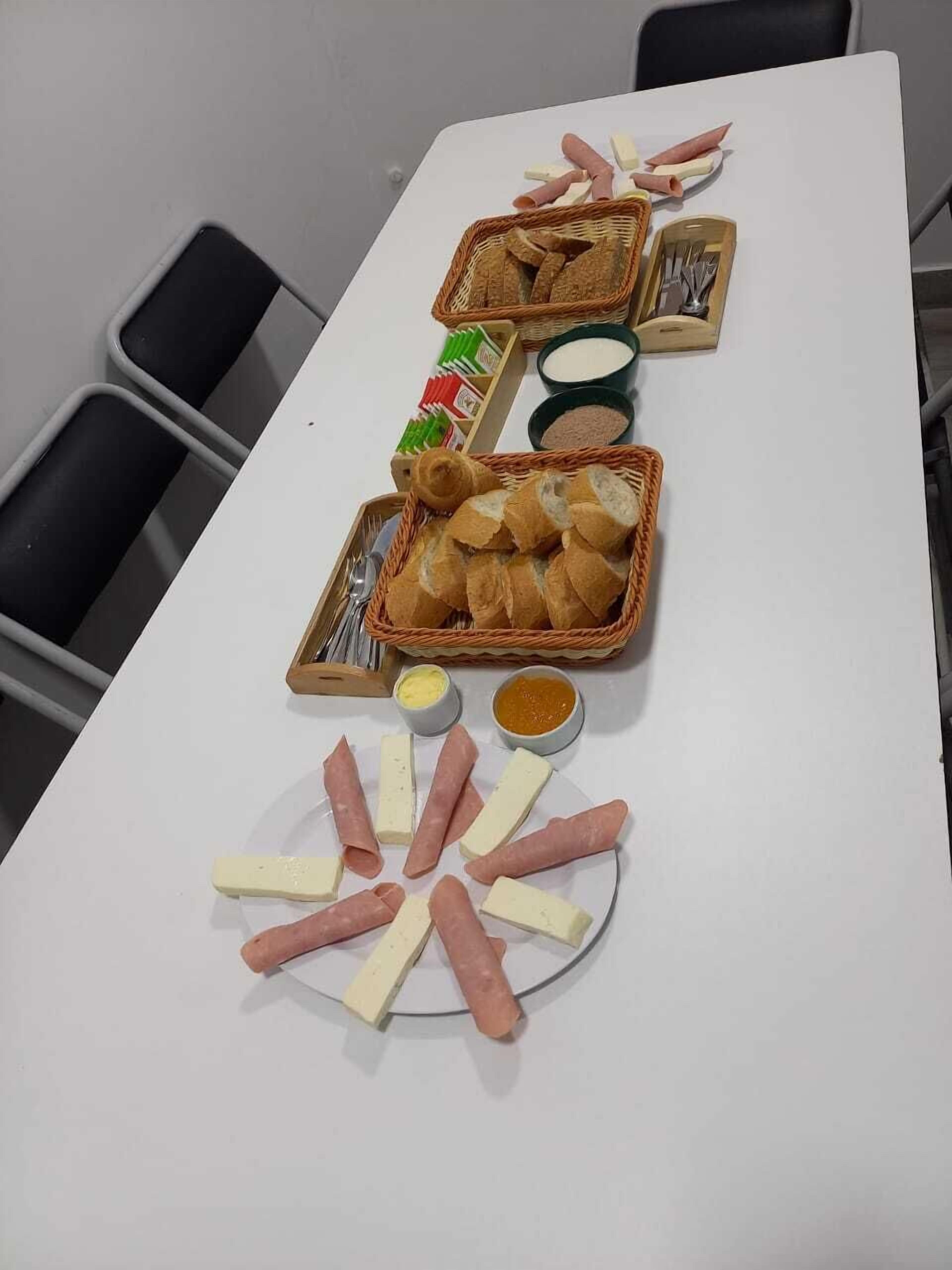 A table with bread, cheese, and meat arranged for a meal.