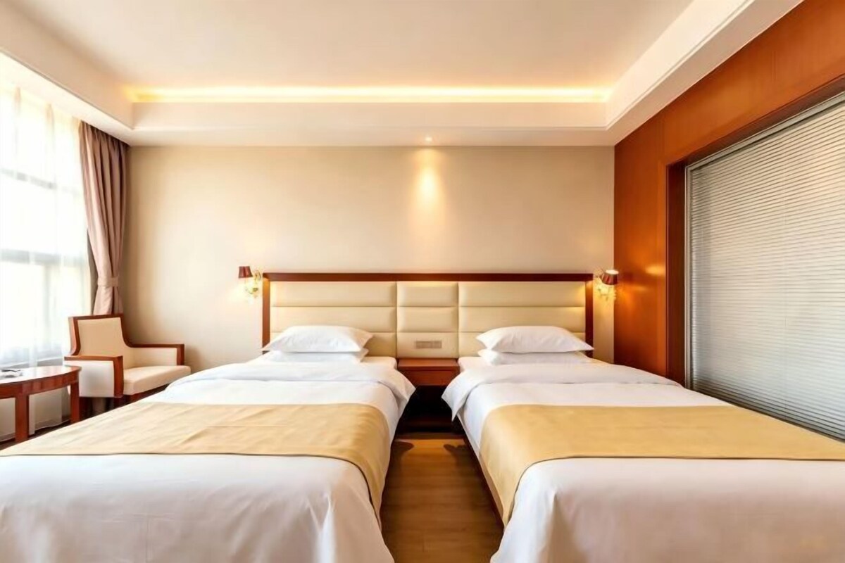 Une chambre d’hôtel avec deux lits, un bureau et une chaise.