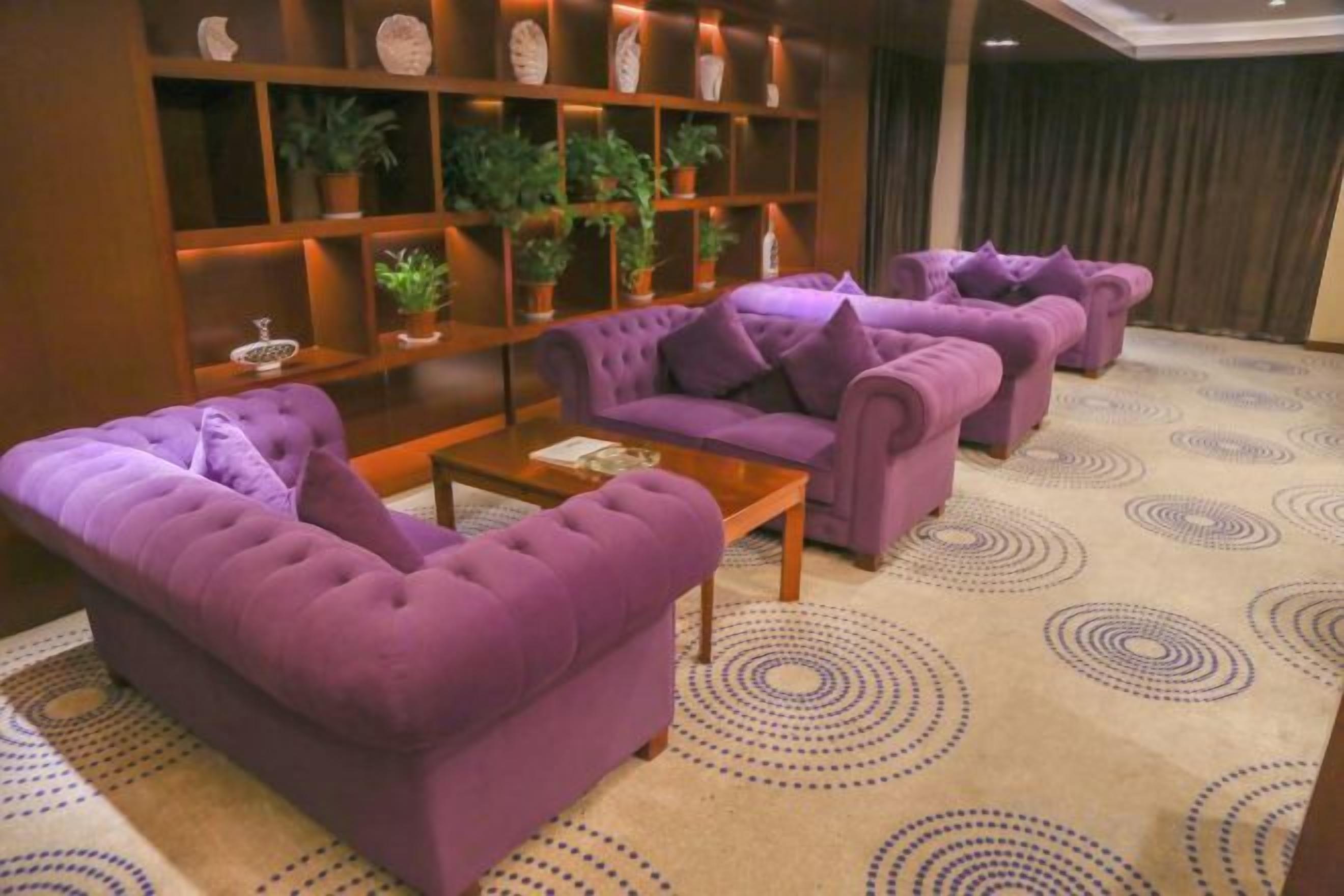A room with purple sofas, a wooden coffee table, and a patterned carpet.