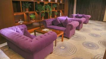 A room with purple sofas, a wooden coffee table, and a patterned carpet.