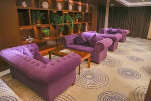 Una habitación con sofás morados, una mesa de centro de madera y una alfombra estampada.