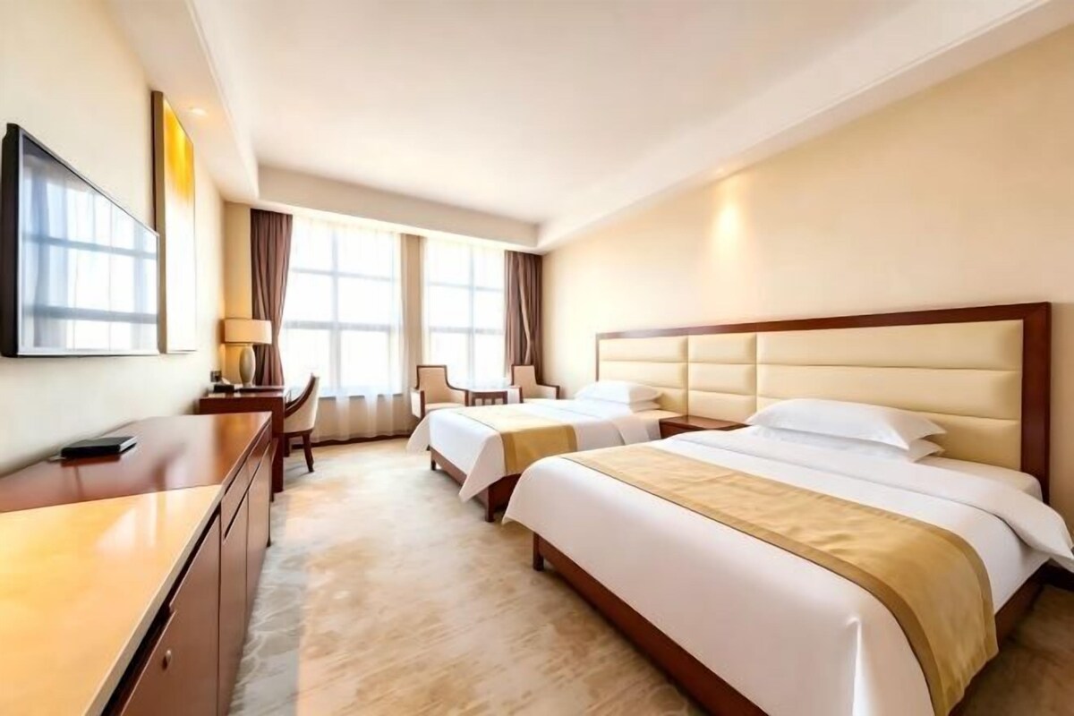 Une chambre d’hôtel avec deux lits, un bureau, une chaise et un téléviseur.