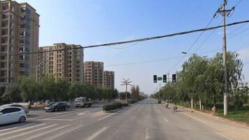 A multi-lane road with traffic lights, vehicles, and buildings in the background.