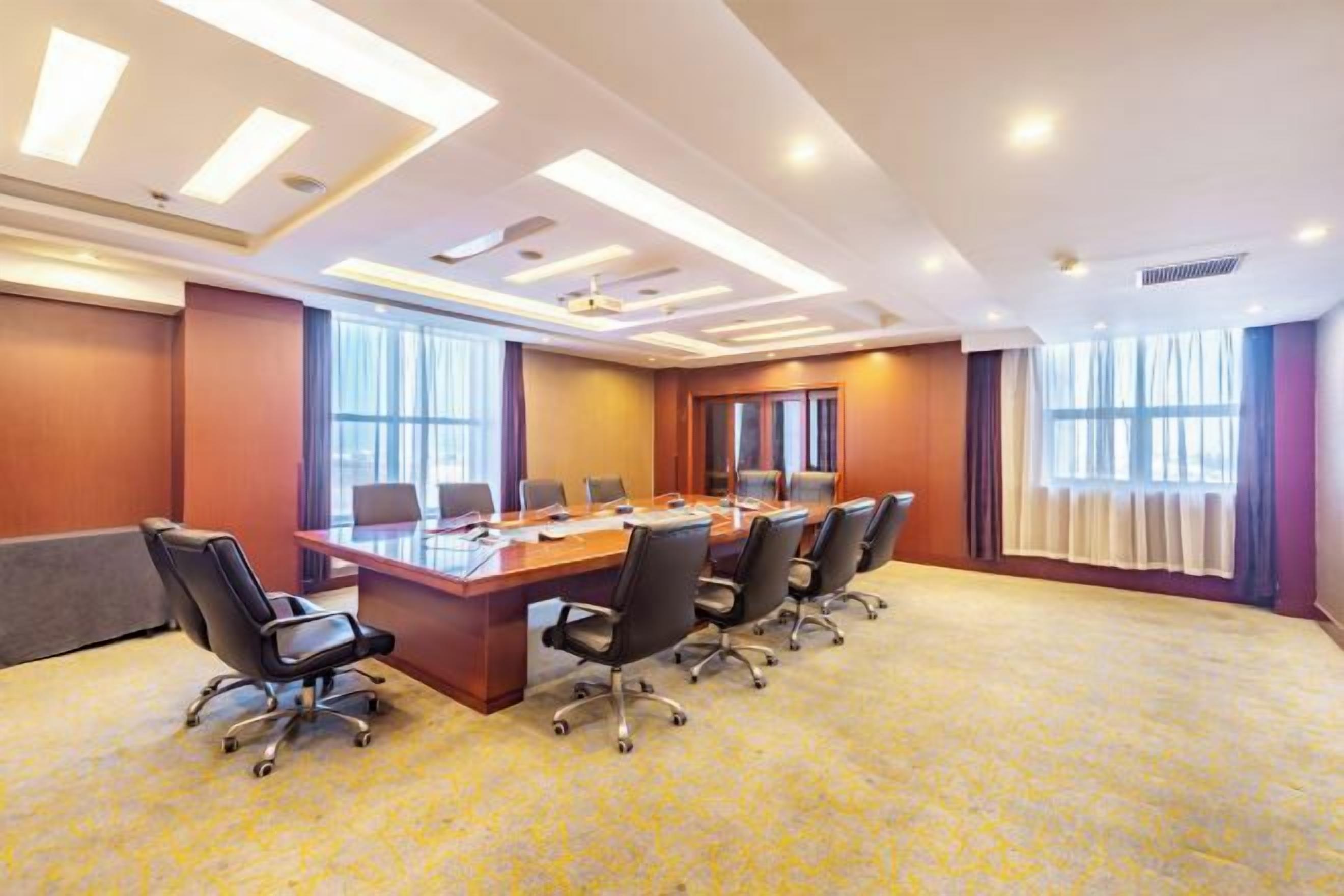 Un salón de conferencias con una mesa larga, sillas y piso alfombrado.