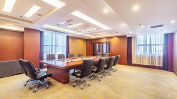 Un salón de conferencias con una mesa larga, sillas y piso alfombrado.