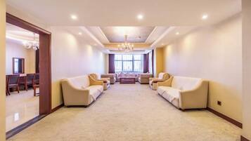 A spacious room with a carpeted floor, two sofas facing each other, and a chandelier.