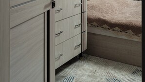 Quarto com guarda-roupa de madeira, cama com colcha estampada e parede decorada.
