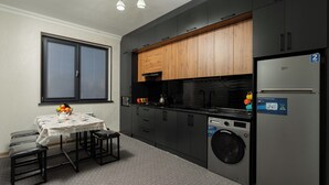 Uma cozinha compacta com máquina de lavar, geladeira e área de refeições com mesa e bancos.
