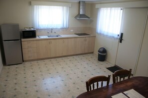 A compact kitchen with a refrigerator, microwave, sink, and cabinets. - Apollo Bay Motel & Apartments (Apollo Bay)