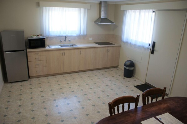Una cocina compacta con refrigerador, microondas, pileta y alacenas.