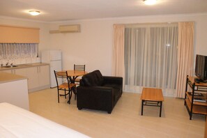 A compact living space with a kitchenette, a sofa, a small table, and a television. - Apollo Bay Motel & Apartments (Apollo Bay)