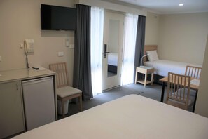 Una camera d'albergo con un letto, una scrivania, una sedia, una televisione e un telefono.
