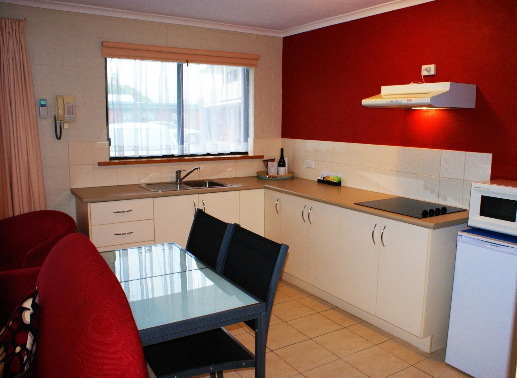 Una cocina compacta con mesa, sillas, microondas y un refrigerador pequeño.