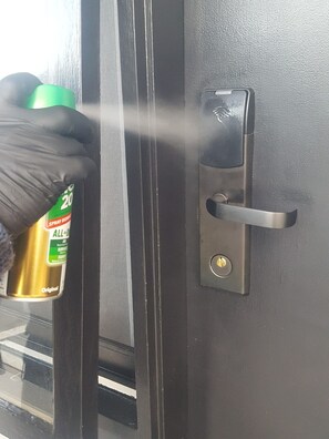 A person using a spray bottle on a door lock. - Apollo Bay Motel & Apartments (Apollo Bay)