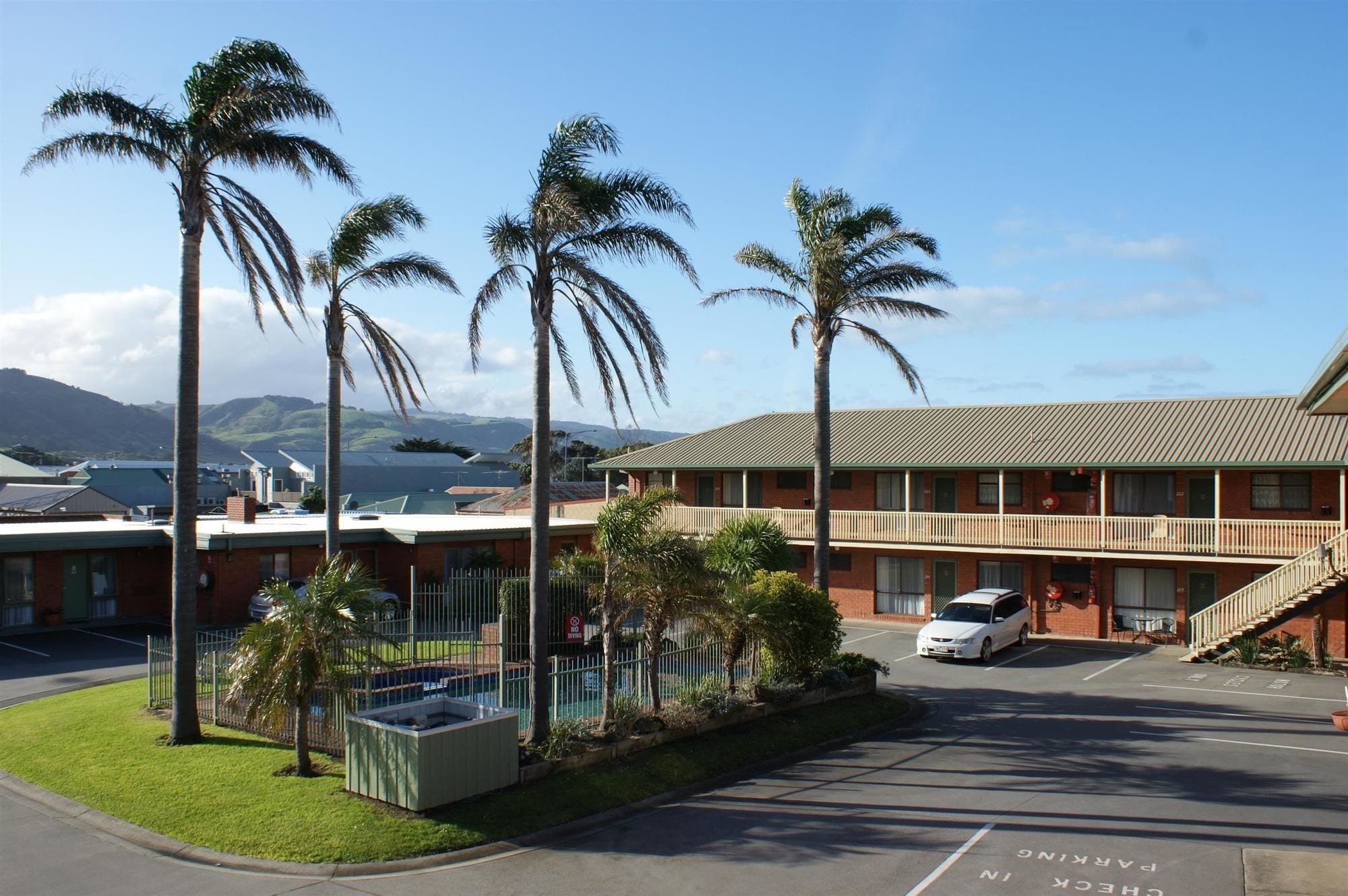 A motel with a parking lot, a pool area, and a view of mountains.
