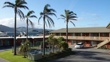 A motel with a parking lot, a pool area, and a view of mountains.