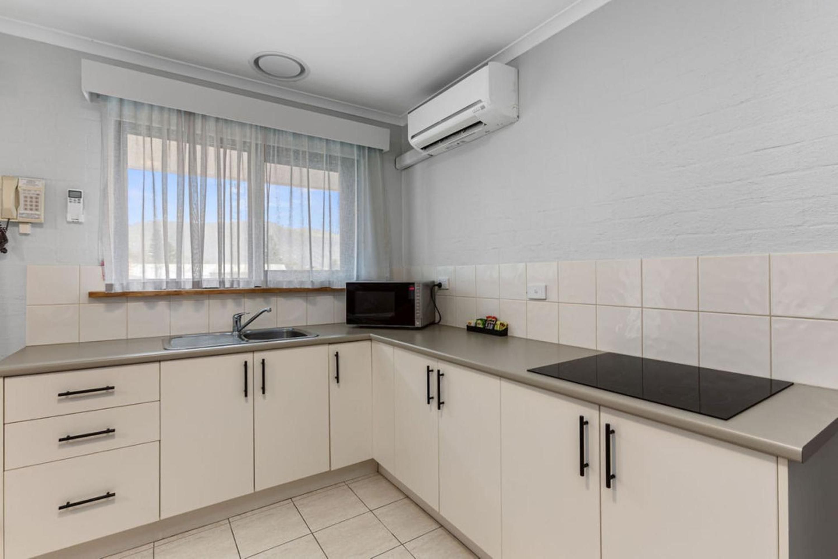 A kitchen with a microwave, a sink, and cabinets.