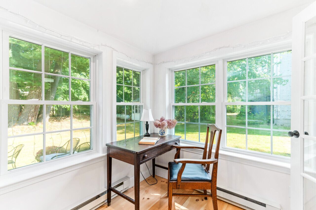 Een hoekappartement met bureau, stoel en grote ramen.