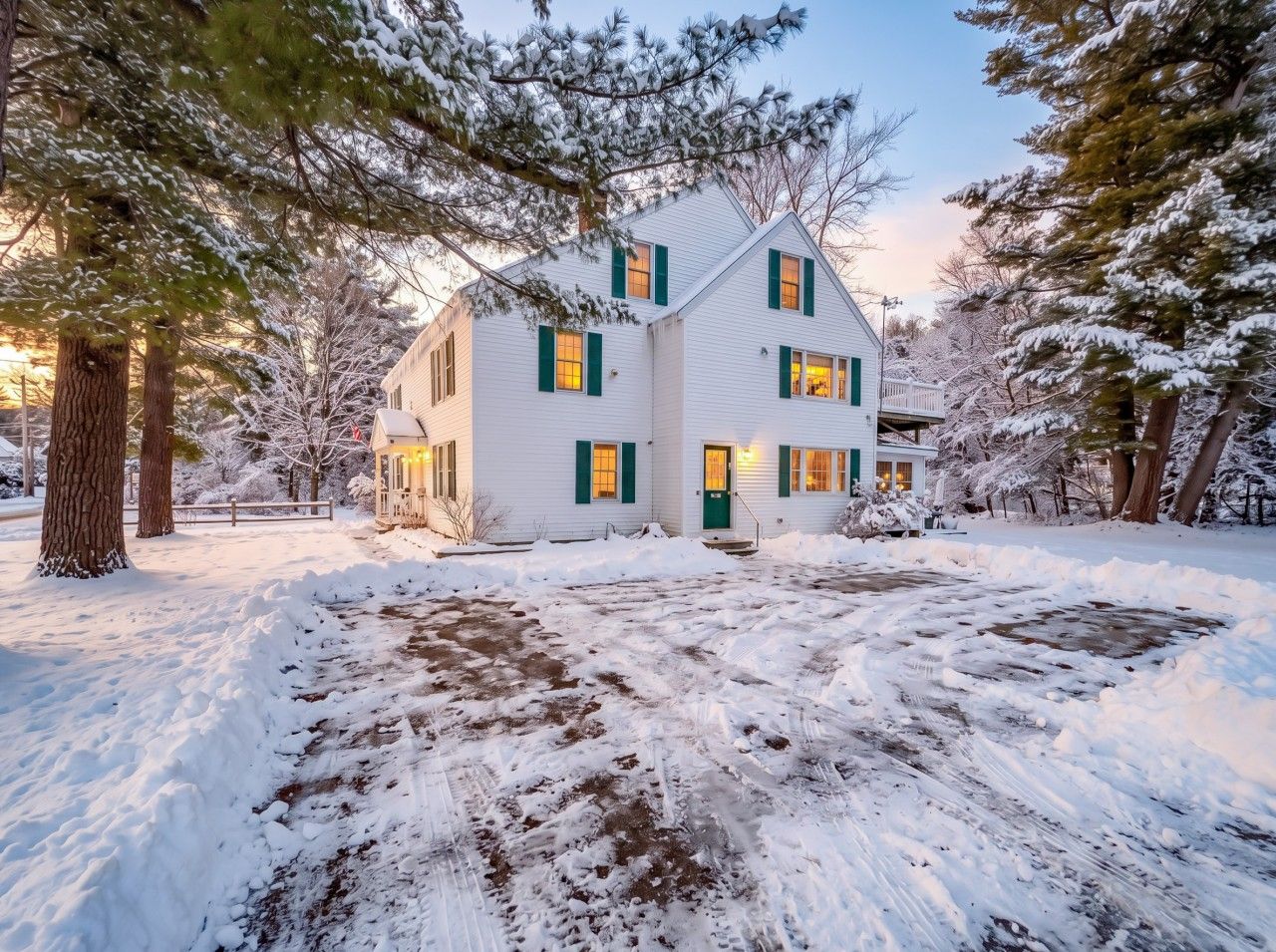 A two-story house with a snow-covered yard and a wooden deck.