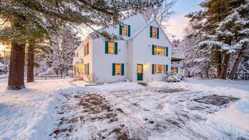 A two-story house with a snow-covered yard and a wooden deck.