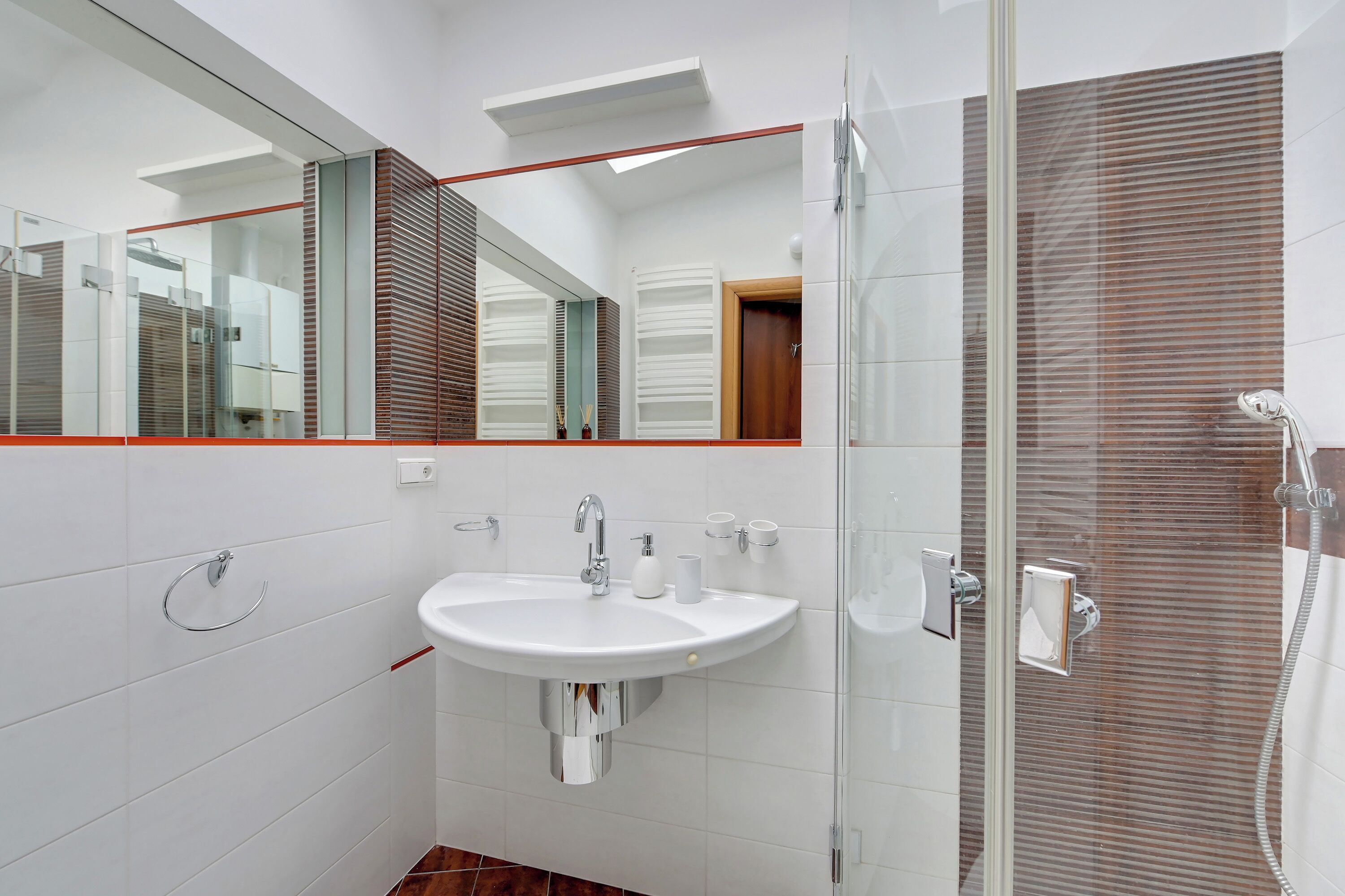 Un bagno moderno con lavandino bianco, specchio e cabina doccia in vetro.