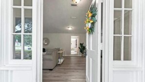 A hallway with a wooden floor, white walls, and a door on the right. - Luxury Vacation Home with private pool. (Jacksonville)