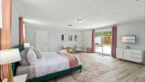 A bedroom with a bed, a nightstand, a lamp, a dresser, and a television. - Luxury Vacation Home with private pool. (Jacksonville)