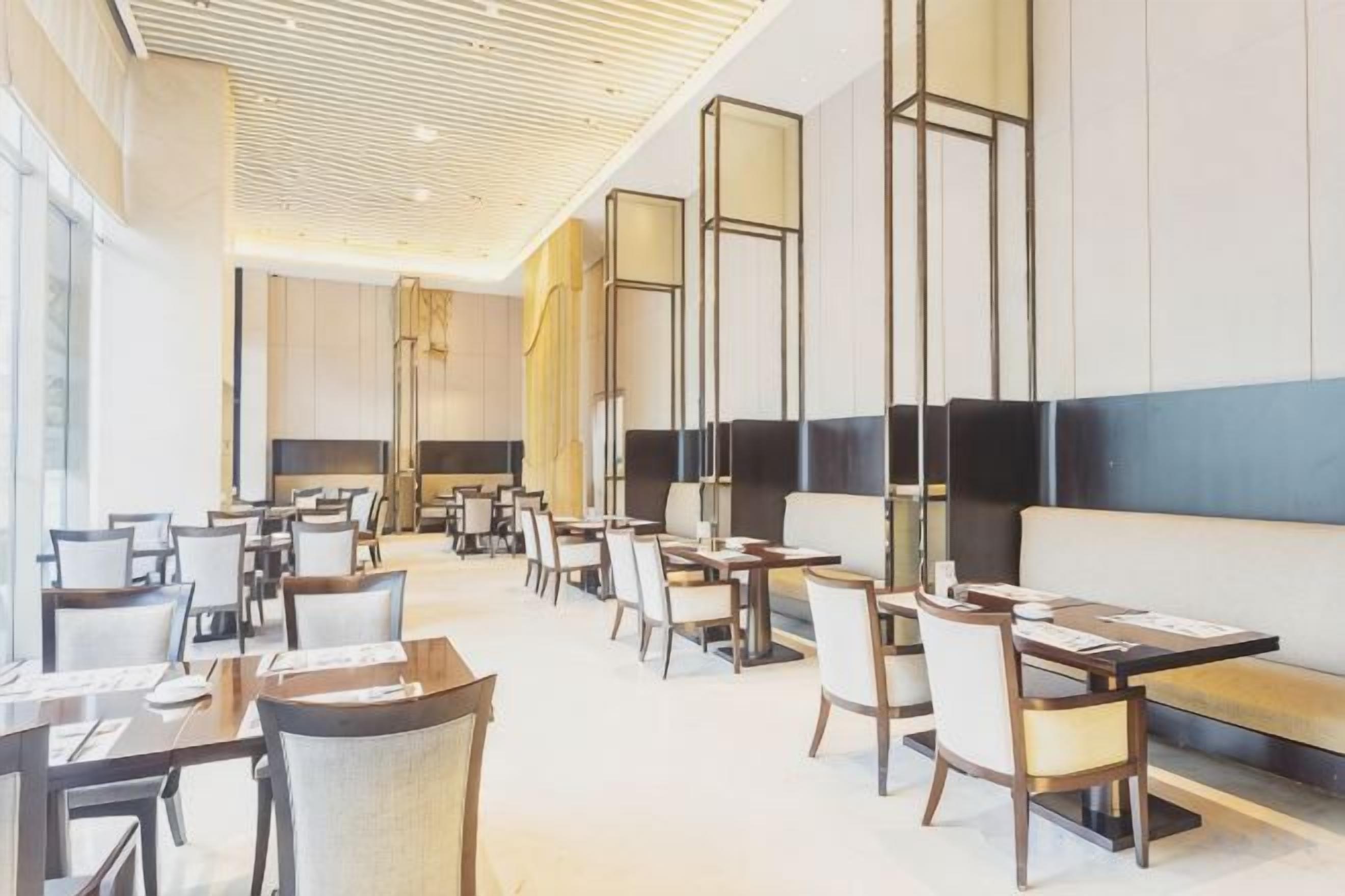 A modern hotel lobby with multiple seating areas, including tables and chairs, and a large sofa.