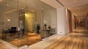 Un vestíbulo de hotel moderno con paredes de vidrio, suelo de madera y un largo pasillo.
